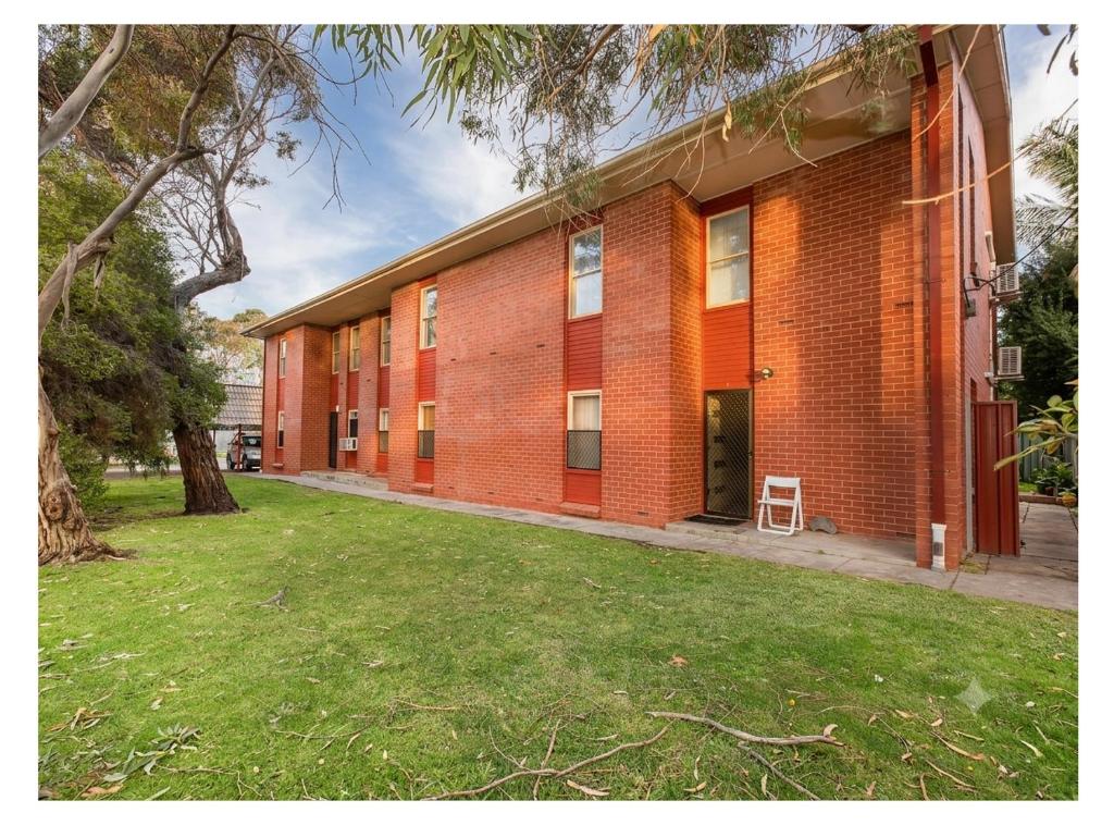 a red brick building with a grass yard at Seaside Adelaide Holiday Apartment 2BR 1 min walk to Brighton Beach in Adelaide