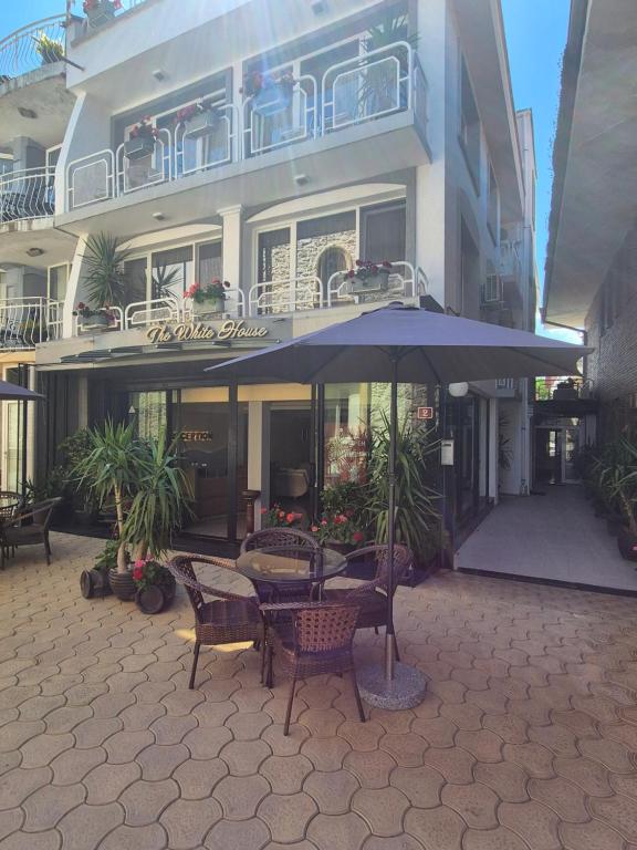 a table with an umbrella in front of a building at The White House Guest House in Nesebar