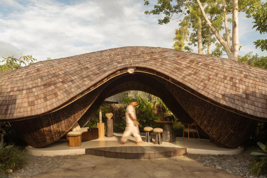 a man walking under a large wicker bridge at Kaymana in Uluwatu