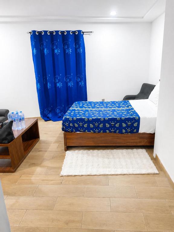 a bedroom with a bed and a blue curtain at TchaoPremium in Lomé