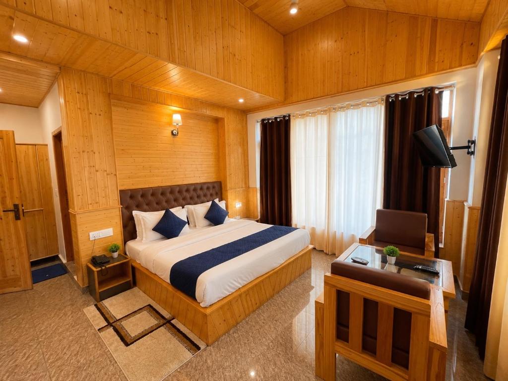 a bedroom with a bed and a desk and a television at Mountain Route Cottage in Manāli