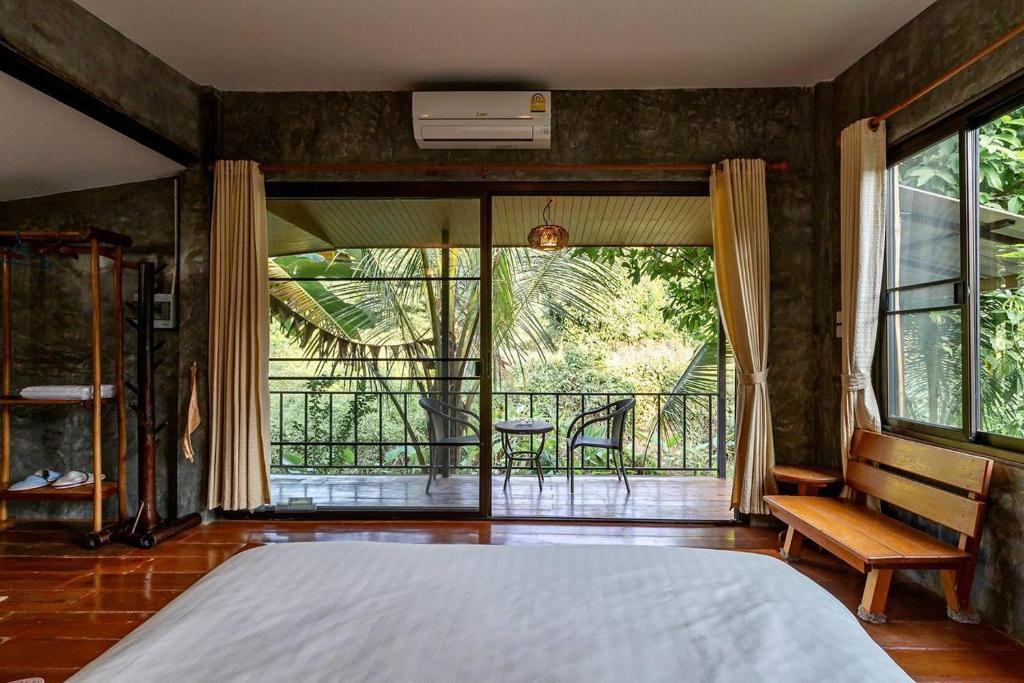 a bedroom with a large bed and a balcony at Lion Cafe Resort in Ban Huai Sieo