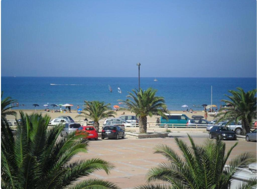 a parking lot at the beach with palm trees and the ocean at Appartamenti Bramante in Vieste