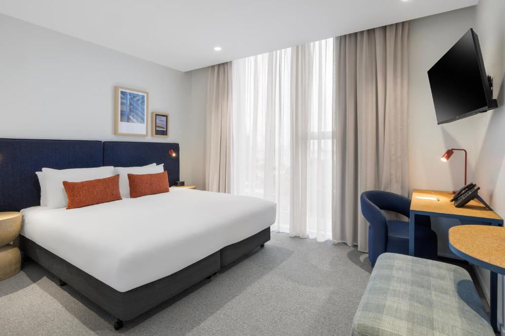 a hotel room with a white bed and a desk at Quest Southport in Gold Coast