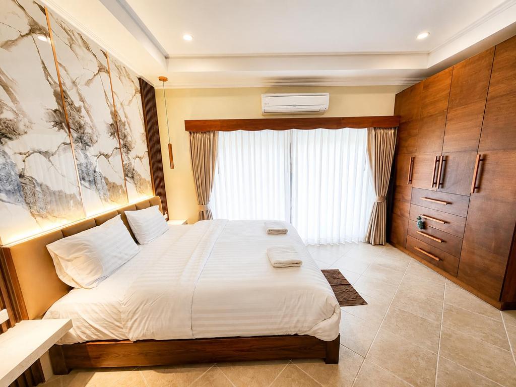 a bedroom with a large white bed with a window at Phratamnak Seaside Pool Villa in Pattaya South