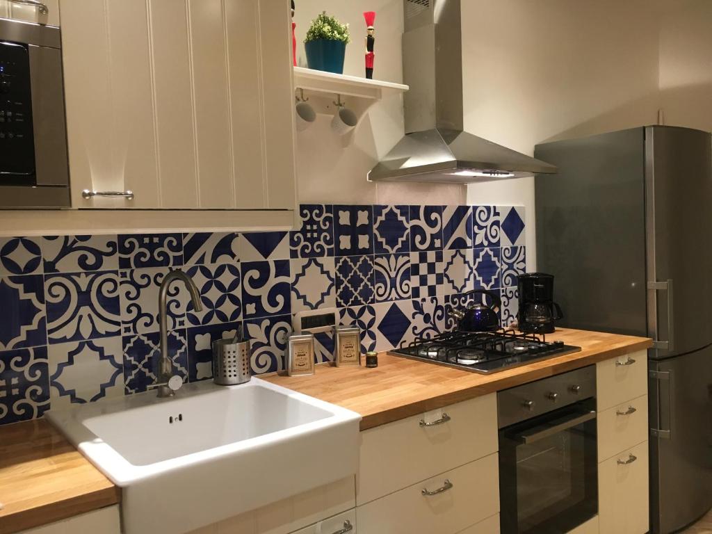 a kitchen with a white sink and blue and white tiles at Fafà Apartment in Naples