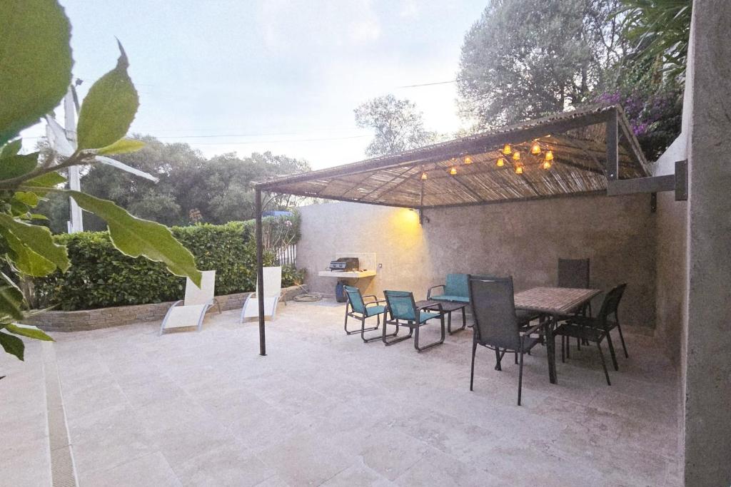 a patio with a table and chairs under a pergola at CASA FOCI - maison T3 in Zonza