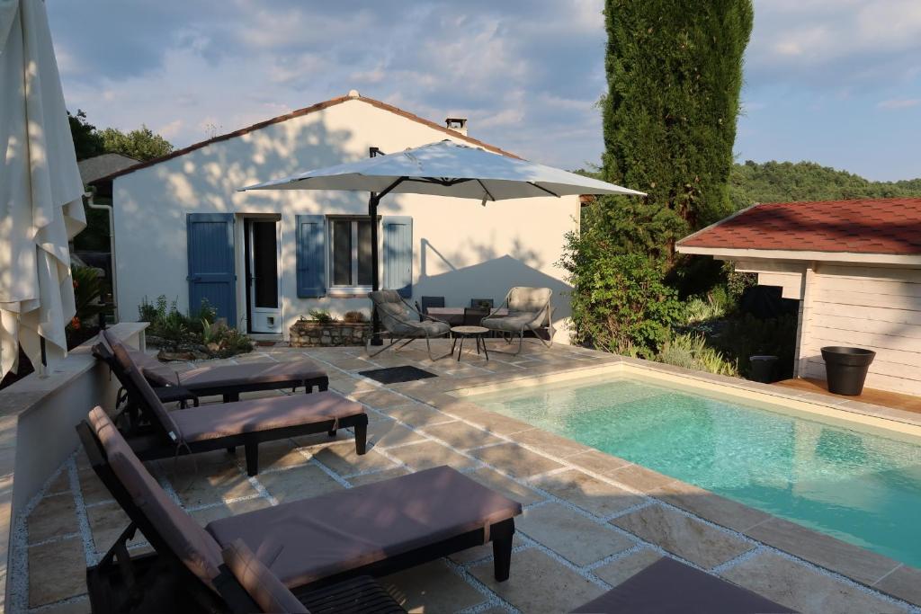 a pool with chairs and an umbrella next to a house at La Vilo Dòu Verdon in Roumoules