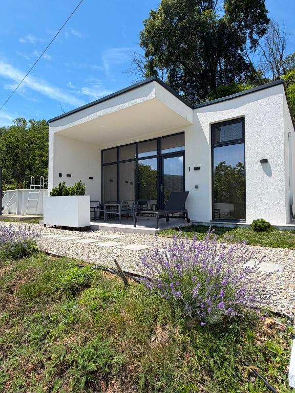a white house with large windows and purple flowers at Nature Nook in Eşelniţa