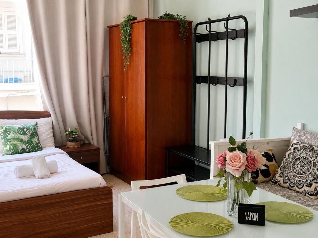 a room with a bed and a table with flowers on it at Oasis - Cosy Studio in Larnaca in Larnaca