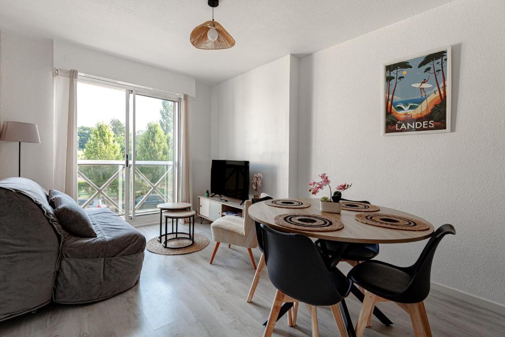a living room with a table and a couch at Appartement Les Jardins in Saint-Vincent-de-Tyrosse
