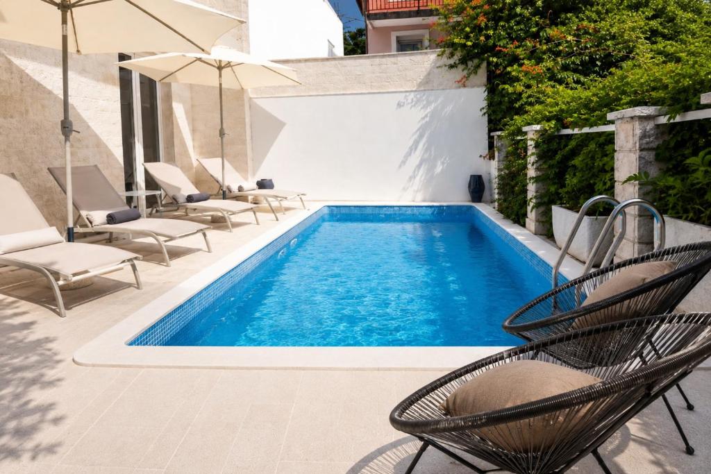 a swimming pool with chairs and an umbrella at Apartman Taraca Villa Knezevic in Herceg-Novi
