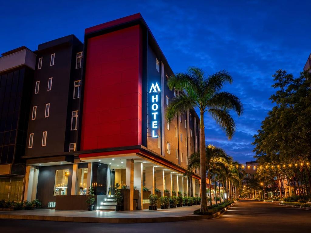 a hotel with a red facade and palm trees at M Hotel Jakarta in Jakarta