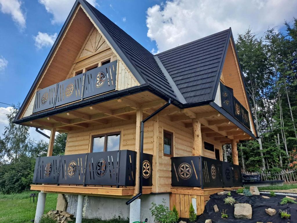 a house with a black roof and a balcony at Domek Góralski Zębianski Dworek in Ząb