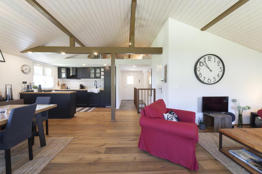 a living room with a couch and a clock on a wall at Chalet Bergblick in Wildhaus