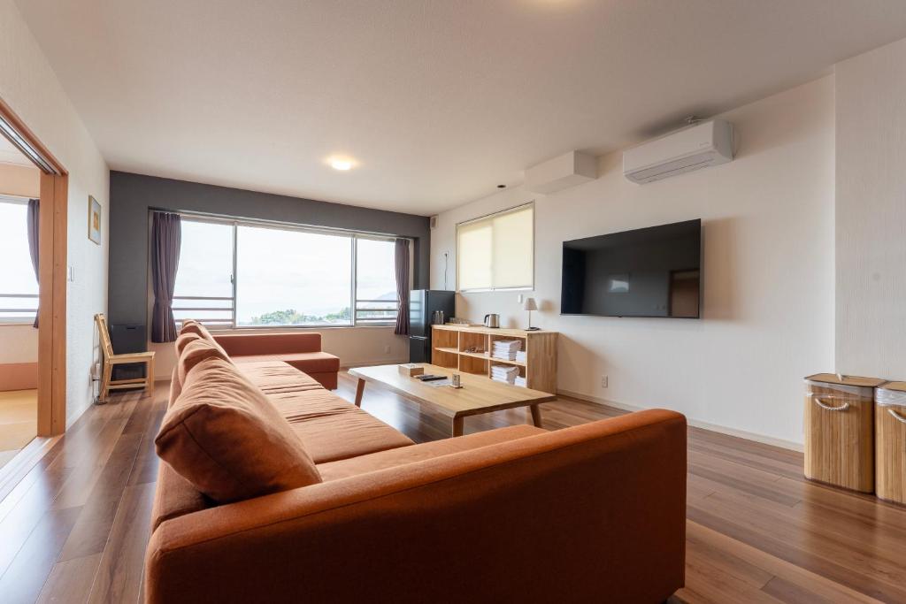 a living room with a couch and a tv at Beppu Ohana in Beppu