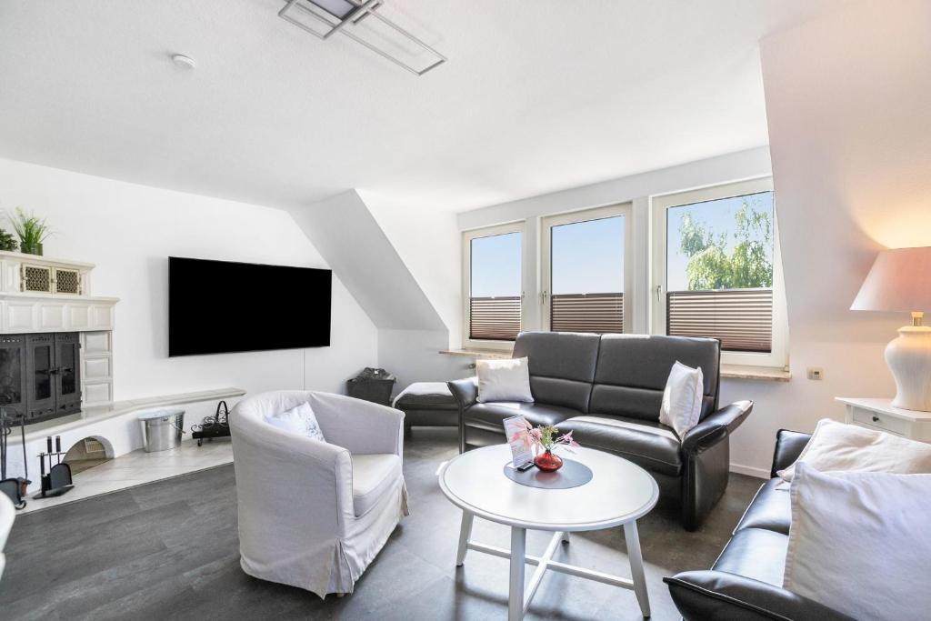 a living room with a couch and chairs and a tv at Fewo Kleine Auszeit 100qm in Friedrichskoog