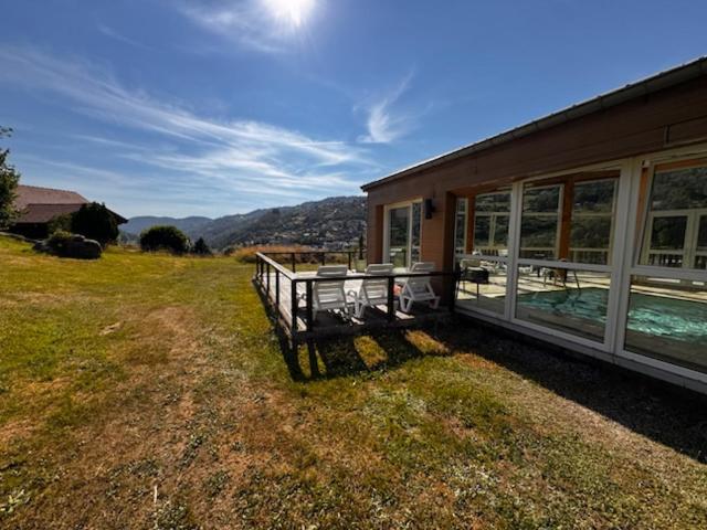 a house with a porch and a swimming pool next to it at Hôtel Restaurant & Bien-être Le Chalet des Roches in La Bresse
