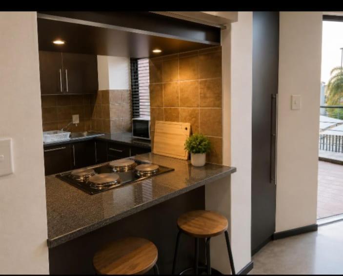 a kitchen with a counter and two stools in it at Staynrestapartment in Nelspruit
