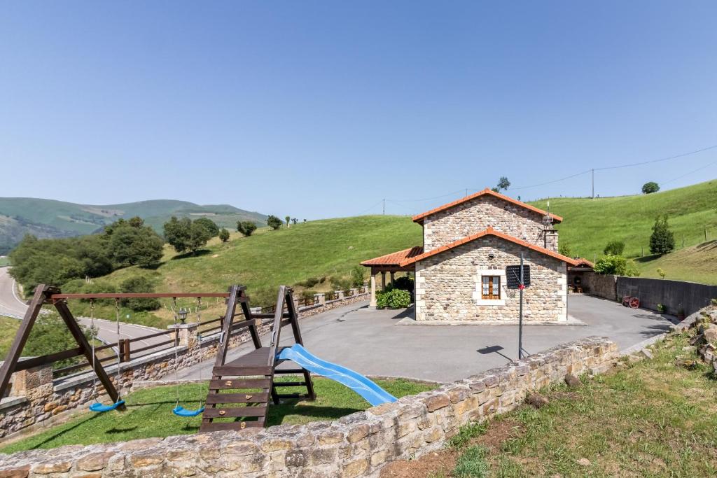 a playground in front of a stone building at La Cabaña de Manuela in Bustantegua