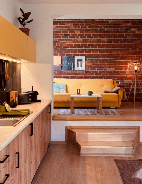 a kitchen with a yellow couch and a brick wall at Bragorski Apartment in Makedonski Brod