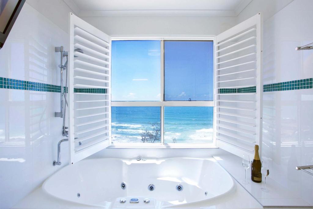 a white bathroom with a tub and a window with the ocean at Villa Seascapes in Coolum Beach