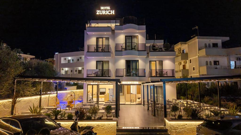 a large white building with a car parked in front of it at Zurich Hotel in Ksamil