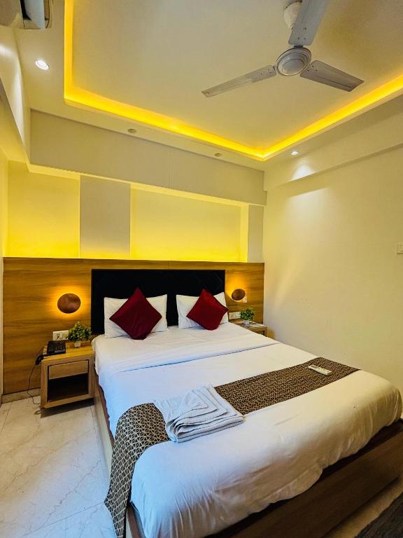 a bedroom with a large white bed with red pillows at Pancharatna Regency in Chinchwad