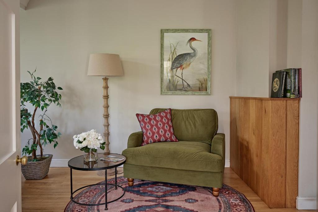 a living room with a green chair and a table at North Lodge at Pudleston Court in Hatfield
