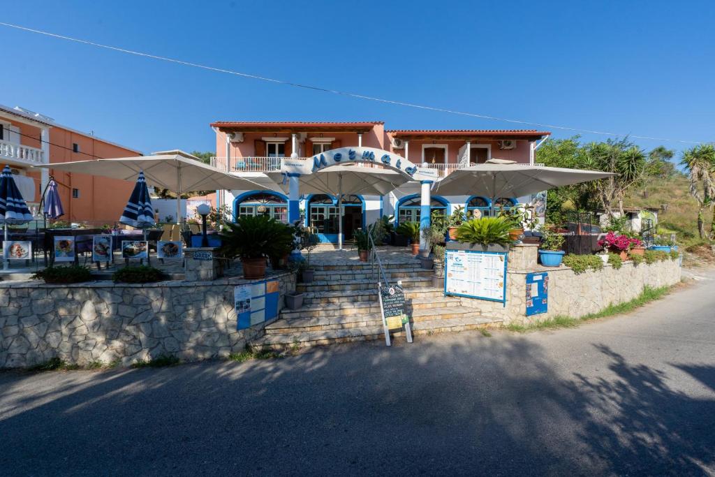 a building with tables and umbrellas in front of it at Mermaids By The Sea in Mesongi
