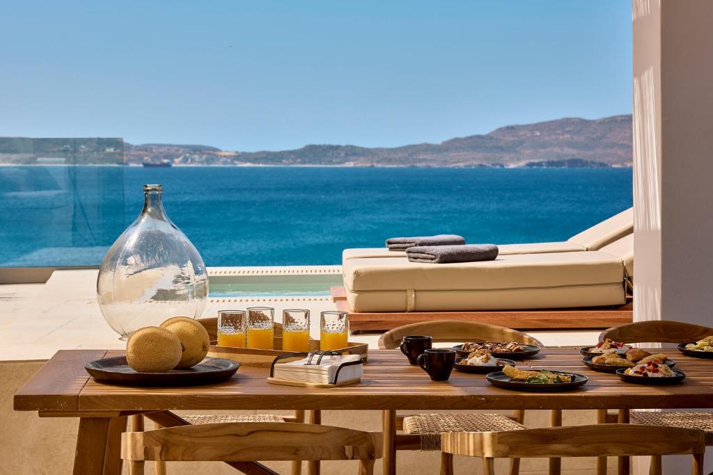 a table with food on it with a view of the ocean at Villa Soleil - Delmar Collection in Adamantas