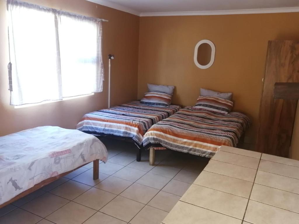 ein Zimmer mit zwei Betten neben einem Fenster in der Unterkunft Skippers Backpackers CC in Walvis Bay