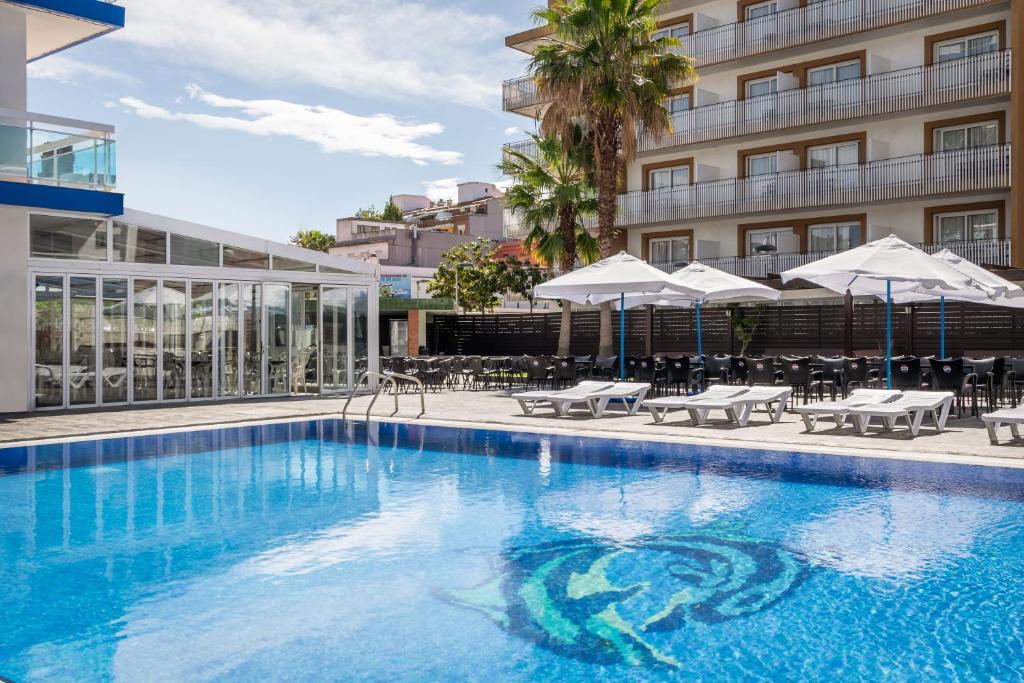a swimming pool with chairs and umbrellas next to a building at Hotel Festa Brava by ALEGRIA in Lloret de Mar