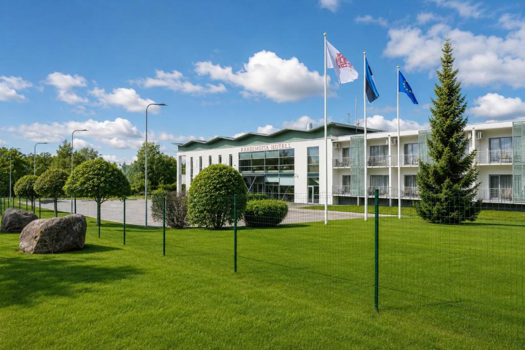 a building with flags in the grass in front of it at Raadimõisa Hotell in Tartu