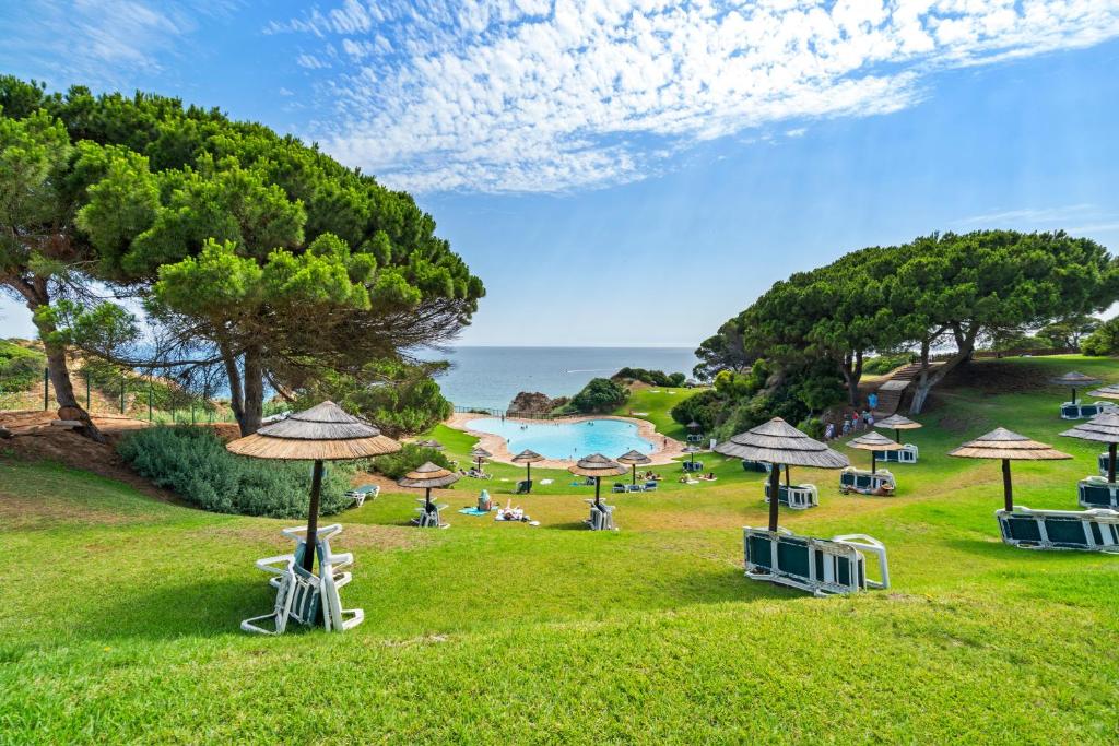 a park with umbrellas and people sitting on the grass at Prainha Alvor - Cozy Villa in Alvor