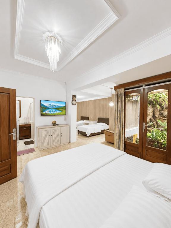 a bedroom with a large white bed and a chandelier at Enny's Guest House in Malang
