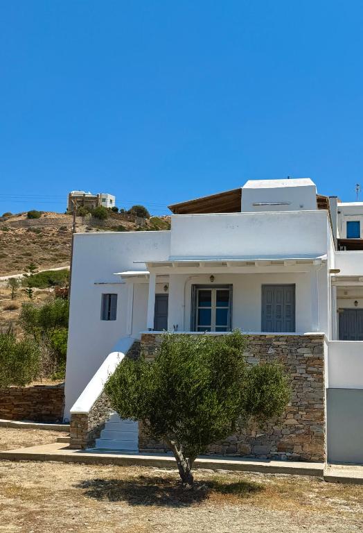 a white house with a tree in front of it at Iosub Houses & Studios - Cosy Seaside House in Koumbara in Tzamaria