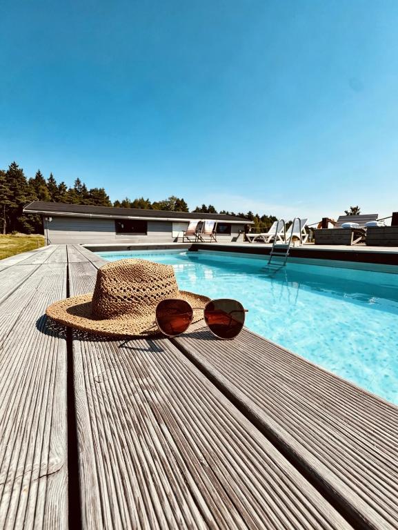 a straw hat and sunglasses sitting on a bench next to a swimming pool at Izerska Baza - basen, ebike, narty, sauna, jacuzzi, las blisko Świeradów Zdrój in Giebułtów