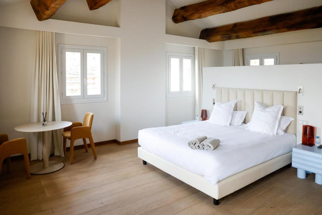 a bedroom with a large white bed and a table at Hôtel Casa Elena in Erbalunga