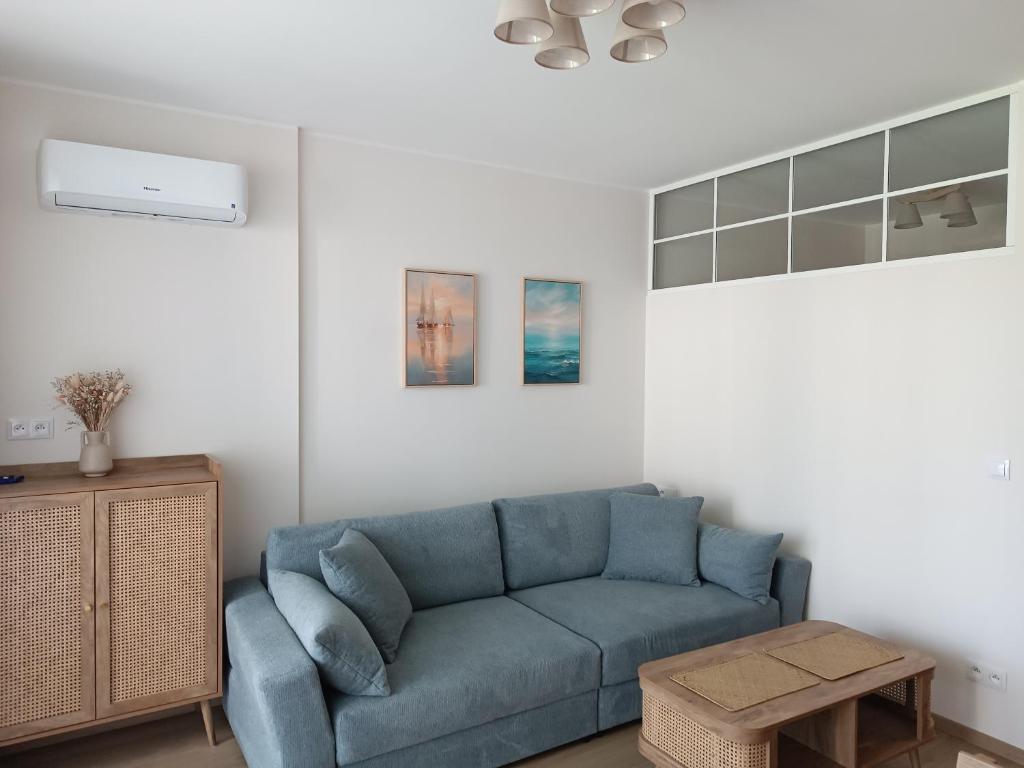 a living room with a blue couch and a table at Apartament 512 in Dziwnówek