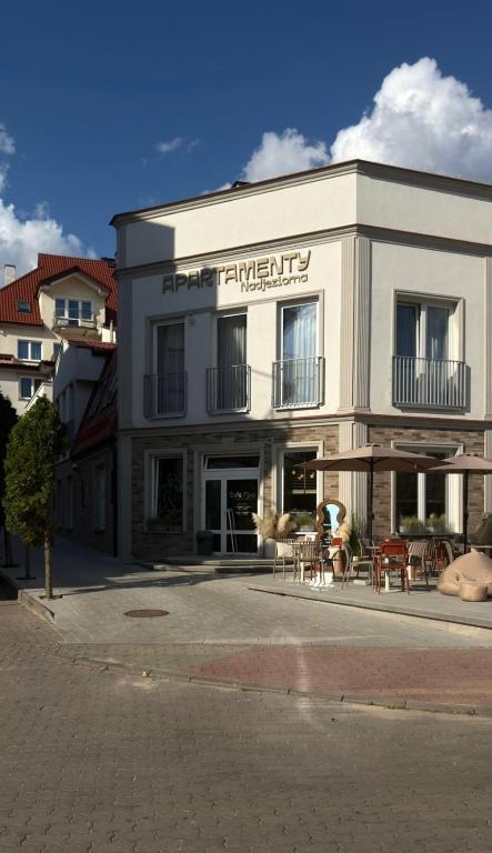 a white building with tables and chairs in front of it at Apartamenty Nadjeziorna in Ełk