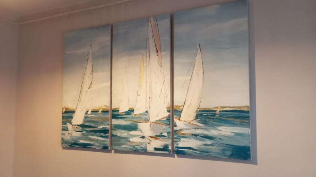 a painting of three sailboats in the ocean at Green Apartman in Čukarica
