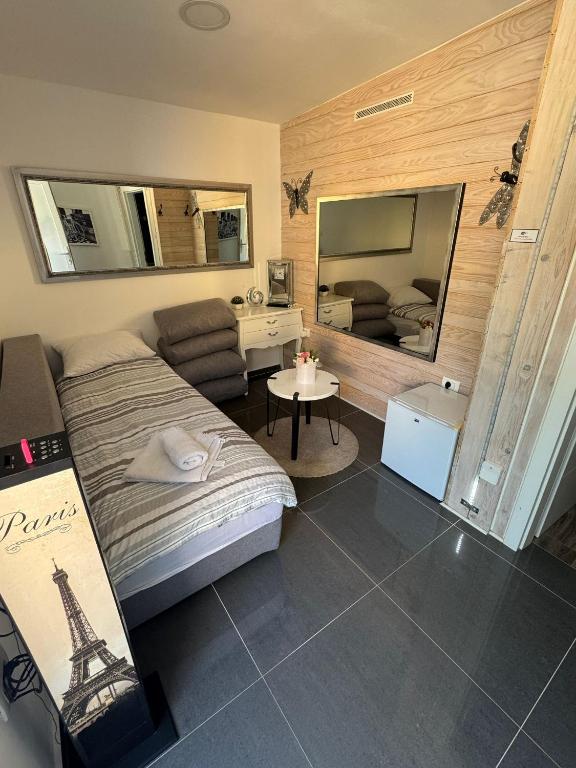 a bedroom with a bed and a chair and a mirror at HA-LU Studio Apartman in Jurdani