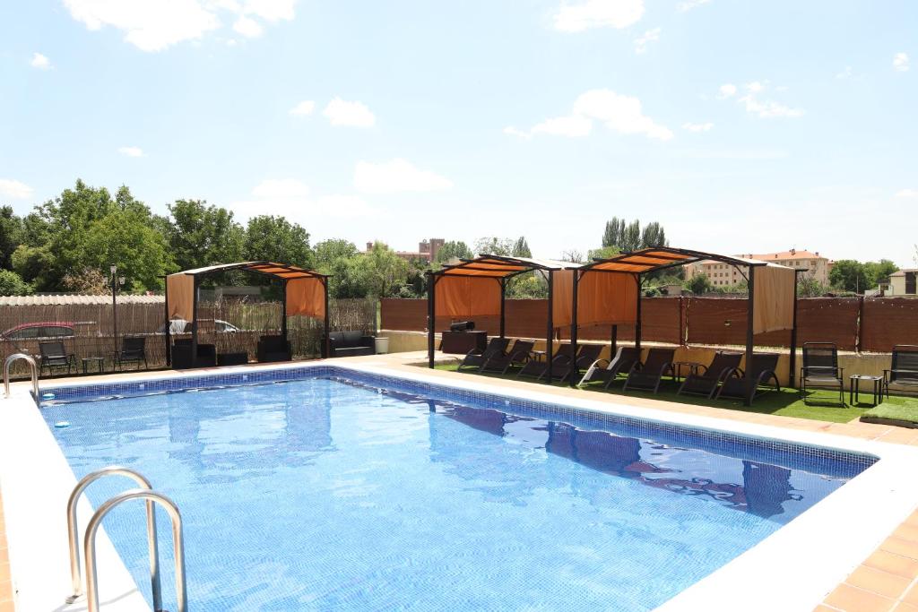 a swimming pool with tables and chairs next to it at Hostal-Casa Rural Rosa-Nonna in Sigüenza