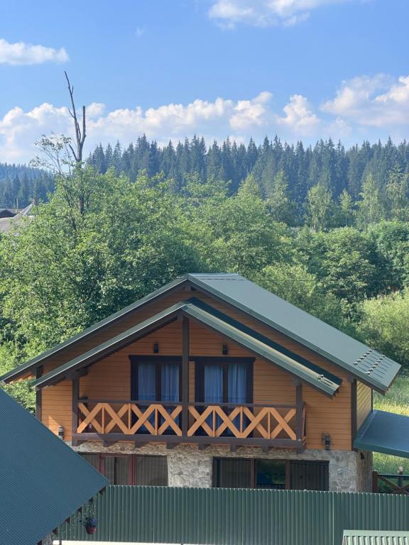 a wooden house with a green fence and trees at Сузірʼя in Vorokhta
