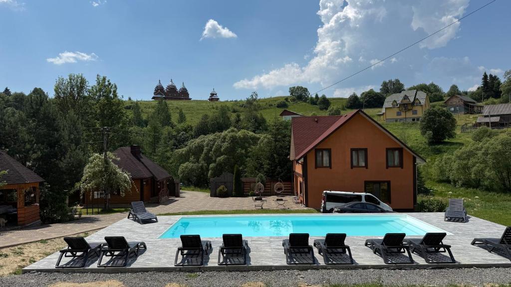 a swimming pool with lounge chairs and a house at U Troh Brativ in Plavie