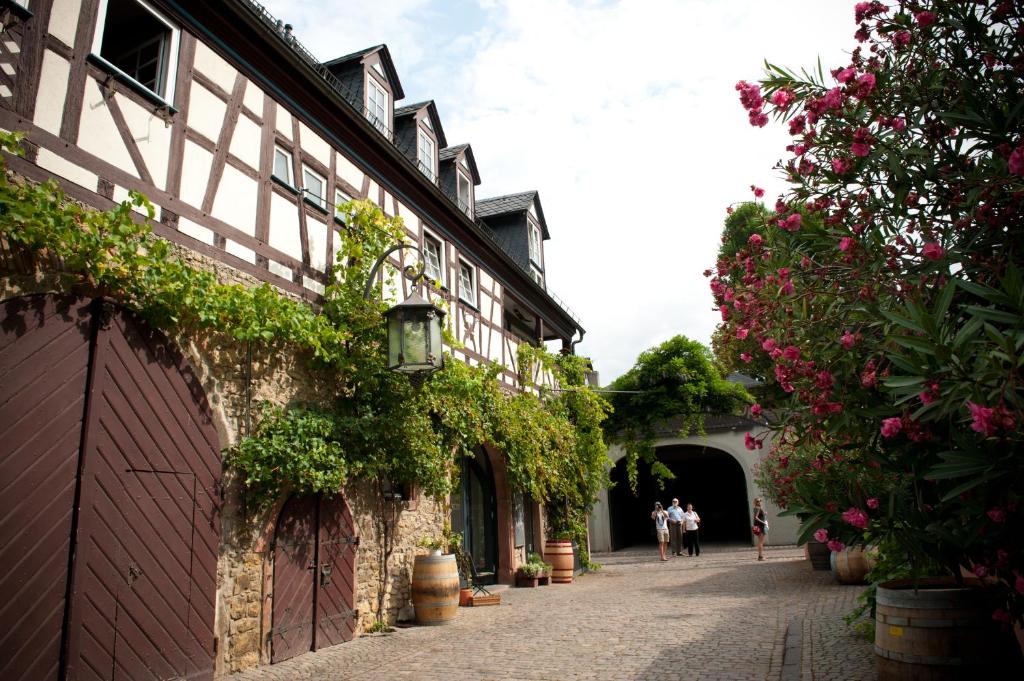 Leute gehen eine Straße entlang, neben einem Gebäude mit Blumen in der Unterkunft Weinhotel Koegler in Eltville