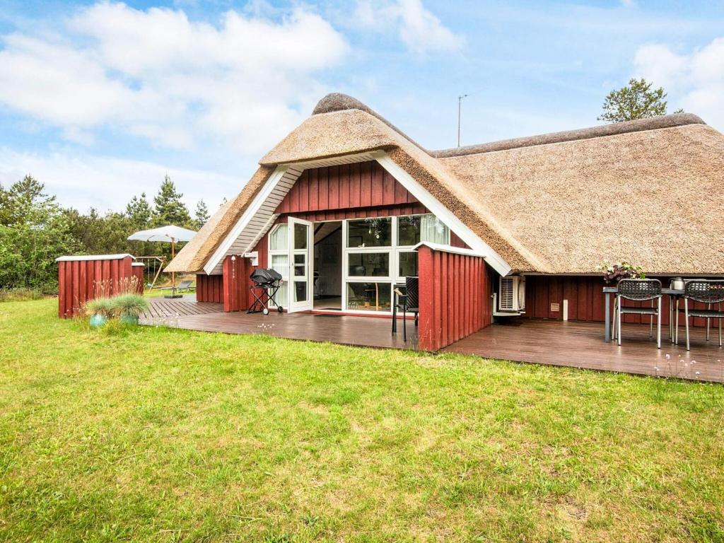 a house with a thatched roof with a deck at 4 star holiday home in Rømø in Kongsmark