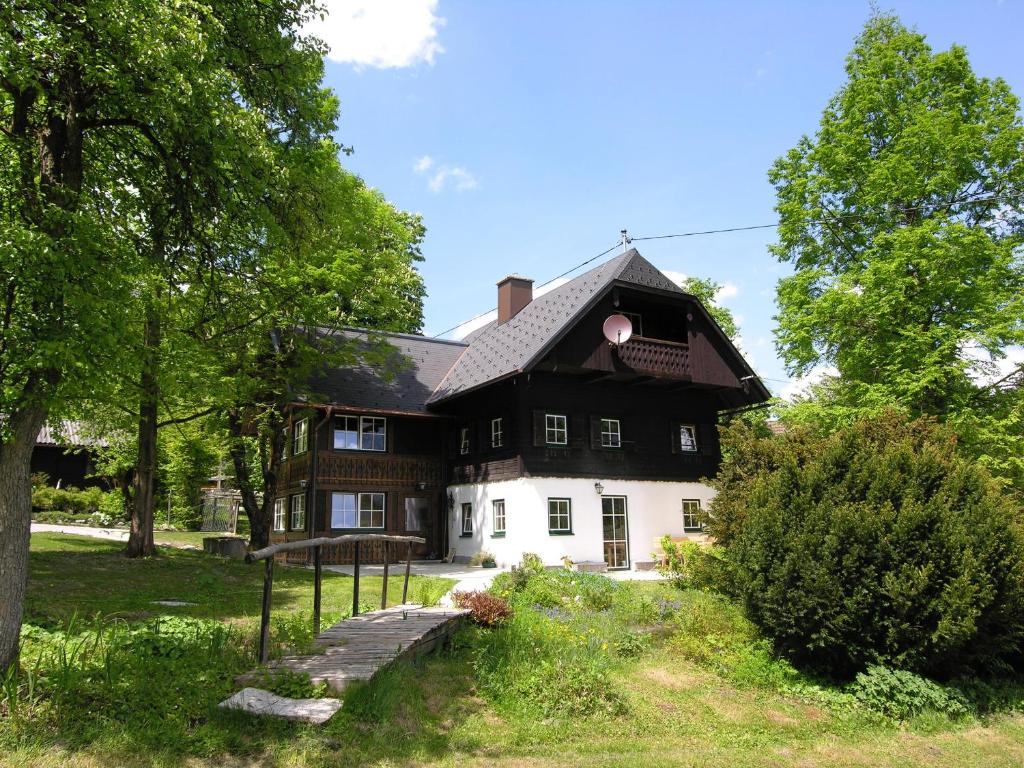 ein schwarzweißes Haus mit Bäumen und Gras in der Unterkunft Ferienhaus Gut - Eisenlehen in Bad Goisern