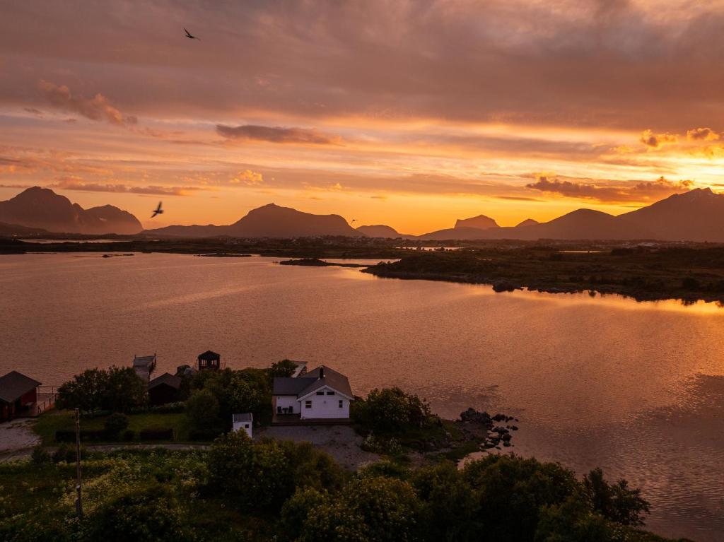 a house on an island in a lake at sunset at Lofoten Oceanfront - Privat Pier & Beach in Vestvågøya